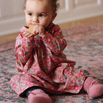 Baby girl wearing Lalaby Anna baby dress in Berry besty pink liberty organic cotton