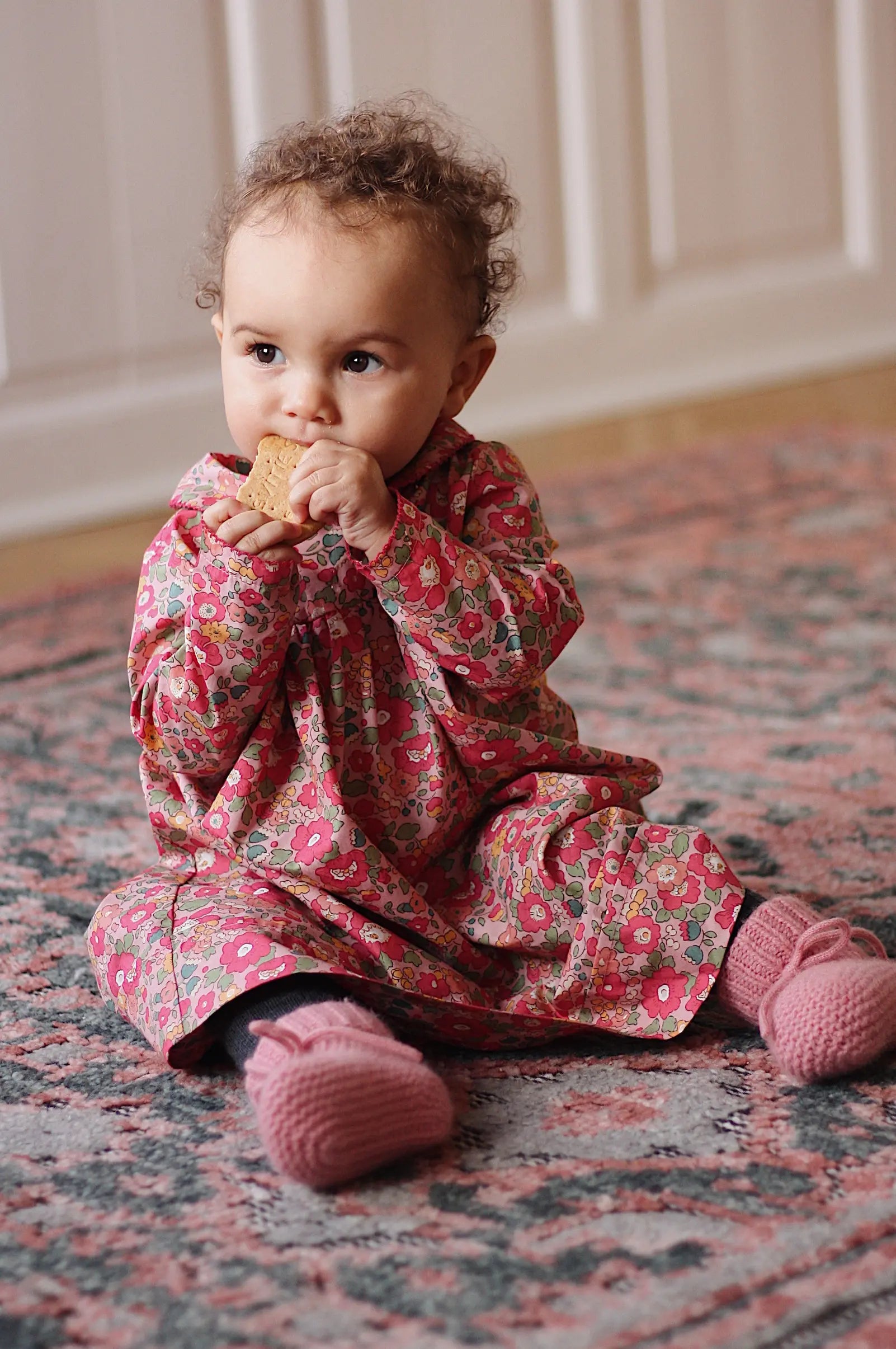 Baby girl wearing Lalaby Anna baby dress in Berry besty pink liberty organic cotton