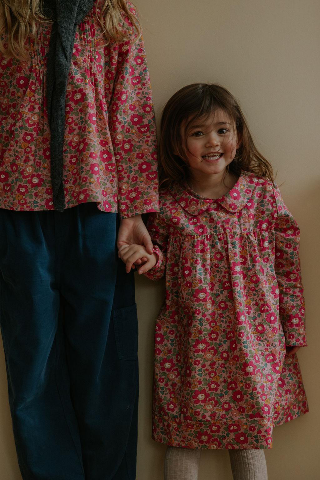 Girl wearing Lalaby Anna dress for kids in berry betsy pink liberty organic cotton