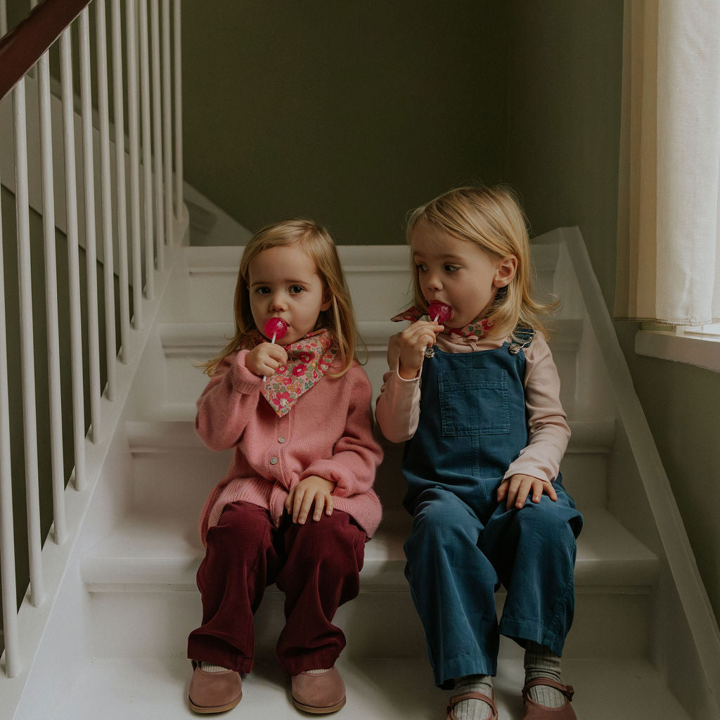 Girl wearing Lalaby Axel trousers for kids in ruby red cotton baby cord