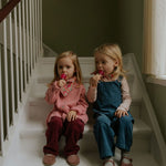 Girl wearing Lalaby Axel trousers for kids in ruby red cotton baby cord