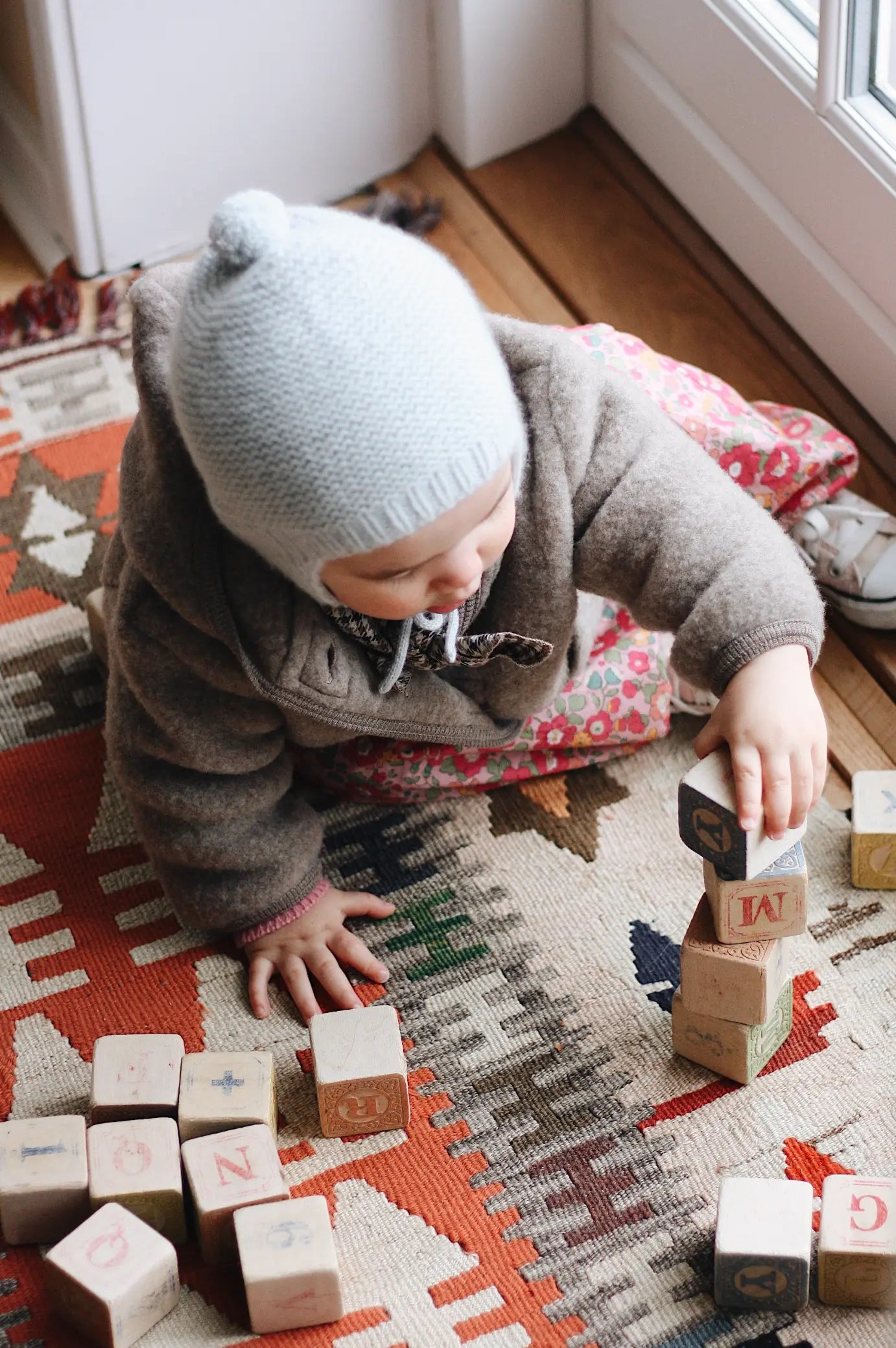 Baby girl wearing Lalaby Babar baby jacket in hazel brown merino wool