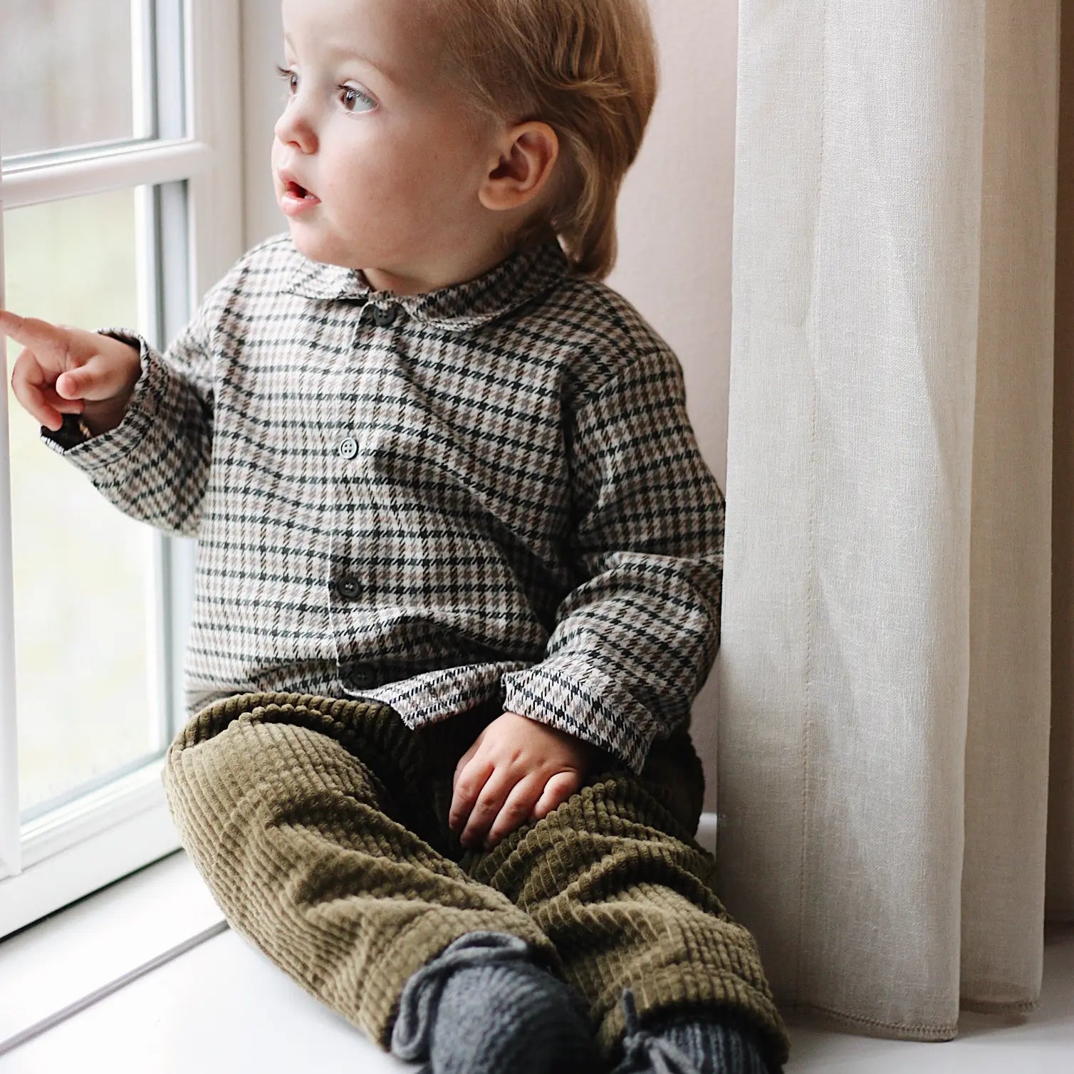 Baby boy wearing Lalaby Charlie baby trousers in forest green cotton mega corduroy