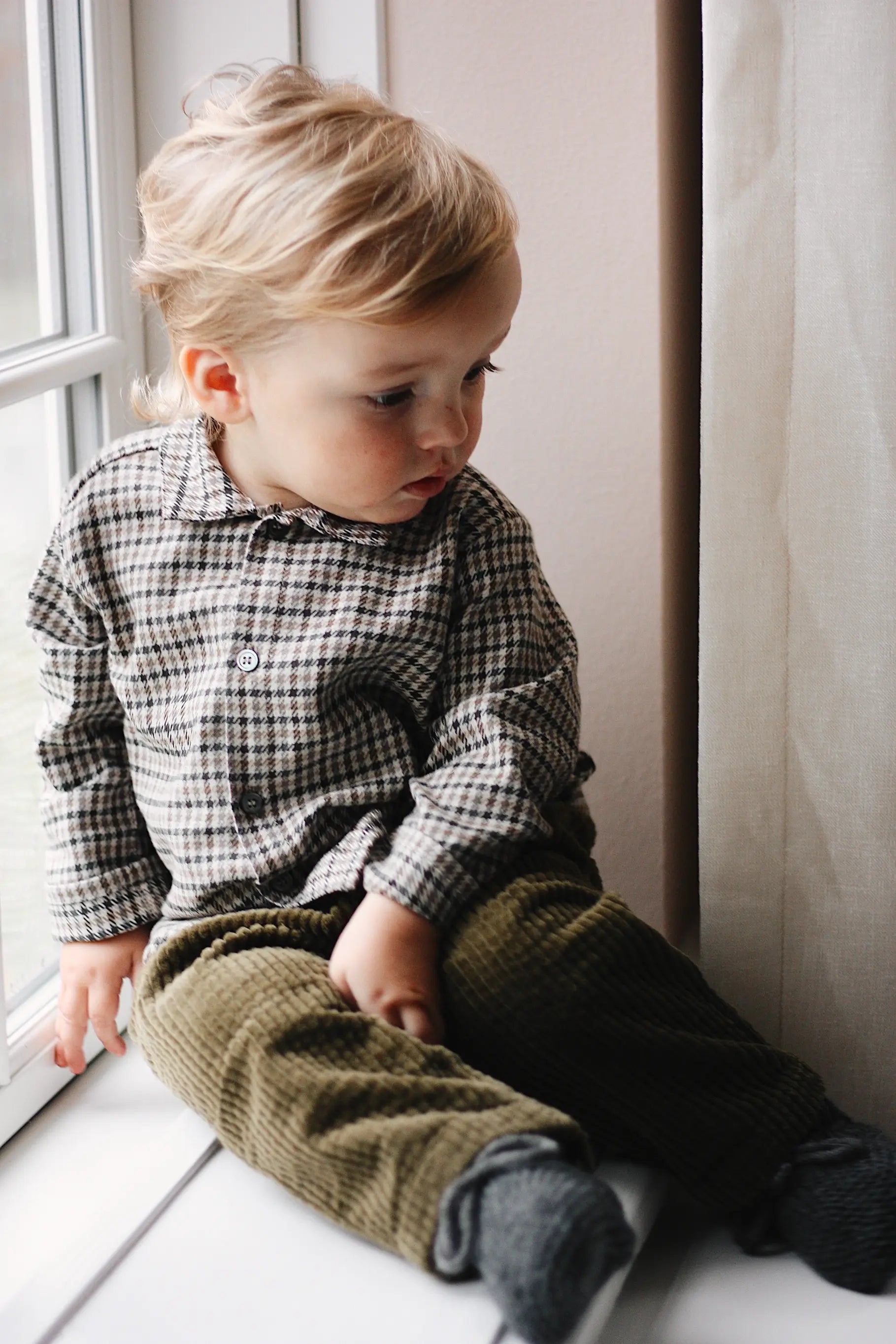 Baby boy wearing Lalaby Charlie baby trousers in forest green cotton mega corduroy