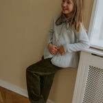 Girl wearing Lalaby Charlie kids trousers in forest green organic cotton mega cord