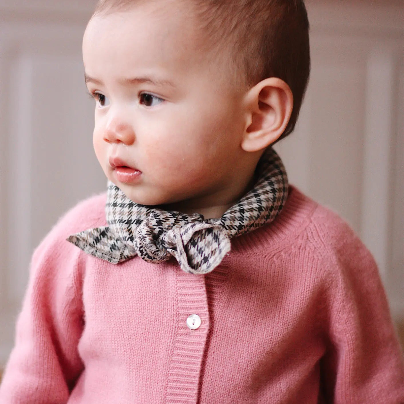 Baby girl wearing Lalaby Eddie scarf for babies and kids in tweedy check organic cotton