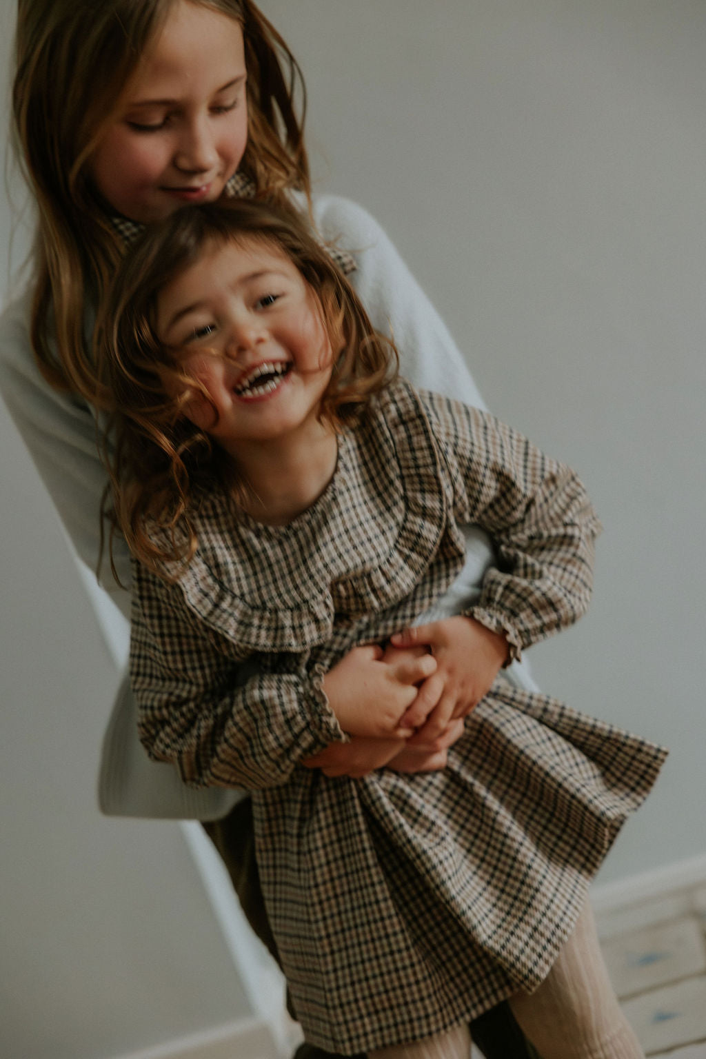 Girl wearing Lalaby Noey dress for kids in tweedy check organic cotton