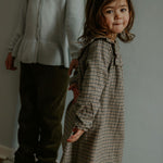 Girl wearing Lalaby Noey dress for kids in tweedy check organic cotton