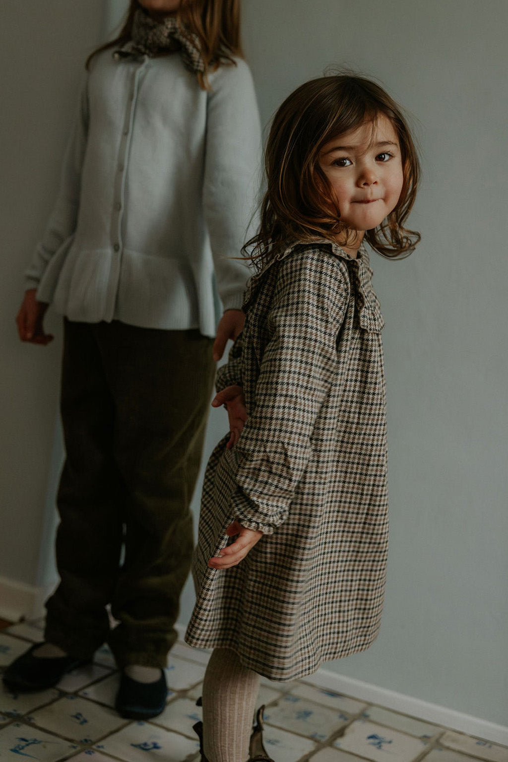 Girl wearing Lalaby Noey dress for kids in tweedy check organic cotton