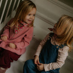 Girl wearing Lalaby Ole overalls for babies and kids in whale blue cotton baby cord