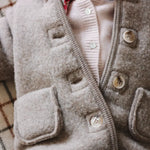 Baby girl wearing Lalaby Teddy baby onesie in hazel brown merino wool