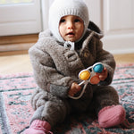Baby girl wearing Lalaby Thule baby onesie in grizzly brown merino wool