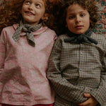 Girl wearing Lalaby Vera scarf for kids and adults in tweedy check organic cotton